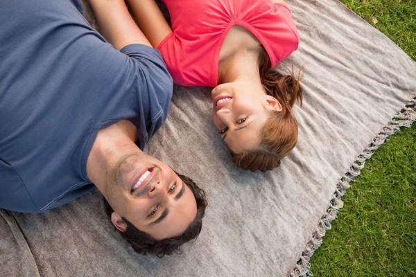 Two friends looking towards the sky while lying on a quilt — Stock Photo, Image