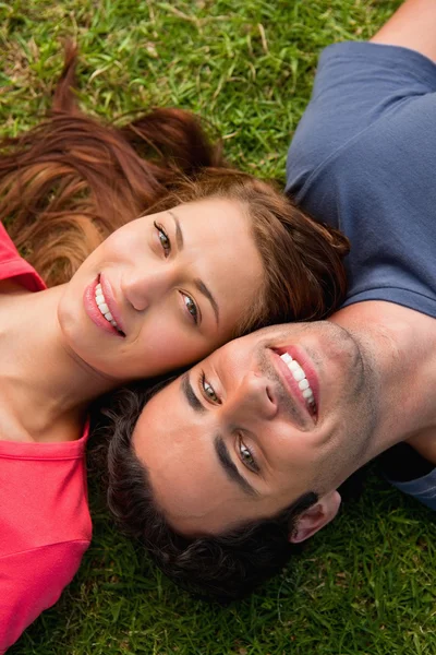 Close-up de dois amigos sorrindo enquanto deitado cabeça a ombro — Fotografia de Stock