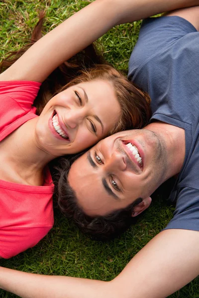 Two friends smiling while lying head to shoulder with an arm out — Stock Photo, Image