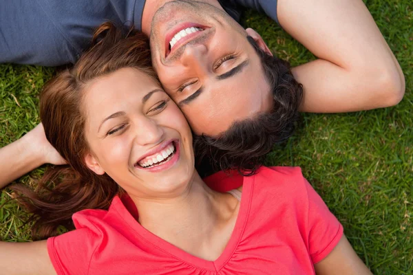 Two friends smiling while lying head to shoulder with an arm beh — Stock Photo, Image