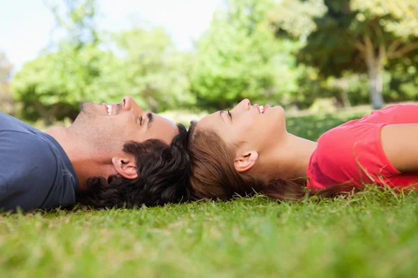 Two friends looking upwards while lying head to head — Stock Photo, Image