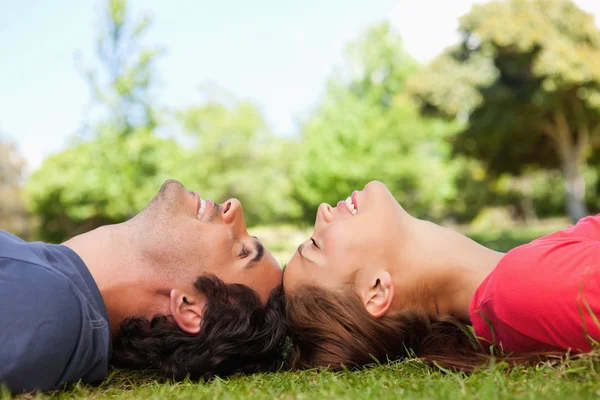 Two smiling friends with their eyes closed while lying head to h — Stock Photo, Image