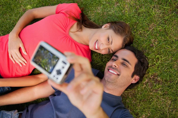 Homem tirando uma foto com seu amigo enquanto estava deitado lado a lado — Fotografia de Stock