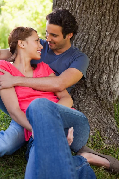 Mann schaut seine Freundin an, wie er sie hält, während sie zusammen sitzen — Stockfoto