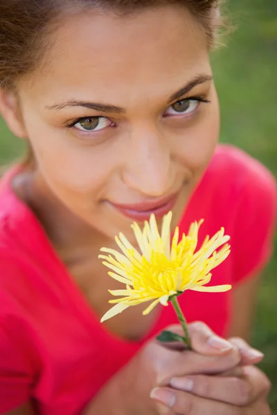 Frau blickt nach oben, während sie eine gelbe Blume in der Hand hält — Stockfoto