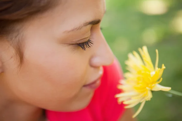 Frau schließt die Augen, als sie eine gelbe Blume riecht — Stockfoto