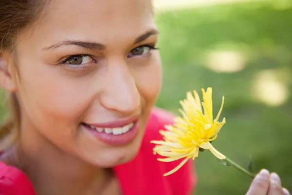 Mujer sonriendo mientras mira hacia arriba mientras sostiene una flor amarilla — Foto de Stock
