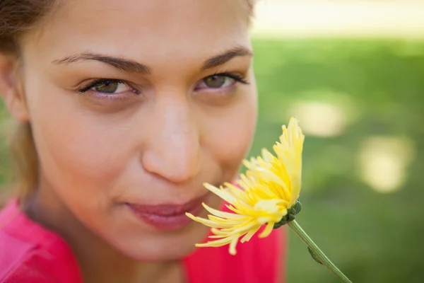 Женщина смотрит вверх, чувствуя запах желтого цветка. — стоковое фото