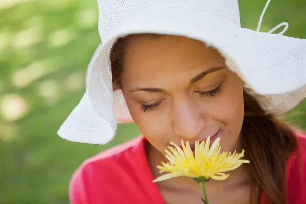 Žena nosí bílý klobouk a vonící květinu s očima — Stock fotografie
