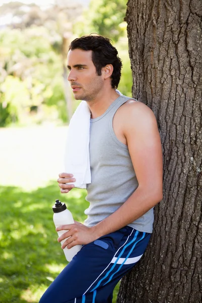 Uomo con un asciugamano sulla spalla, tenendo una bottiglia sportiva mentre — Foto Stock
