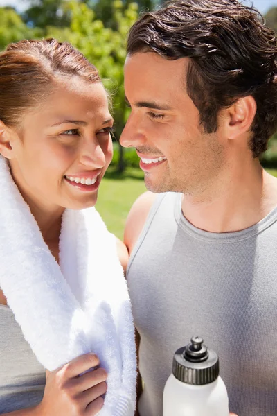 Smiling woman holding a towel while looking at a man — Stock Photo, Image
