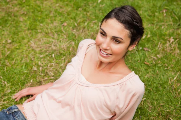 Mulher sorrindo enquanto ela se deita na grama — Fotografia de Stock