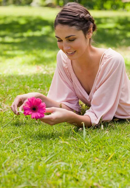 Frau liegt auf ihrer Vorderseite, während sie eine Blume hält — Stockfoto