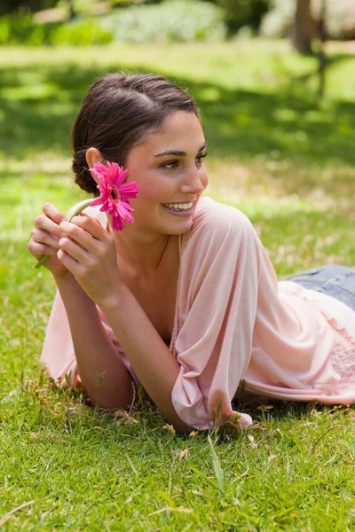 彼女の側に探していると花を保持しながら横たわっている女性 — ストック写真