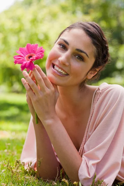Frau, die ihr Kinn an den Händen hält, während sie eine Blume hält — Stockfoto