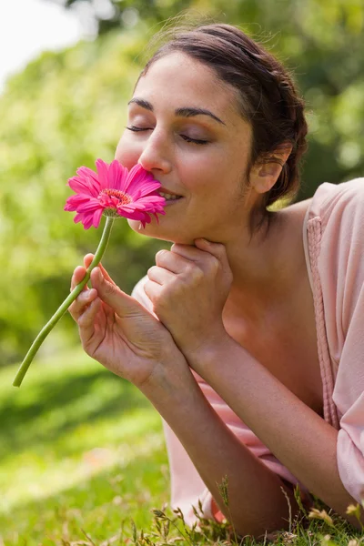 Frau riecht eine Blume, während sie auf ihrer Vorderseite liegt — Stockfoto