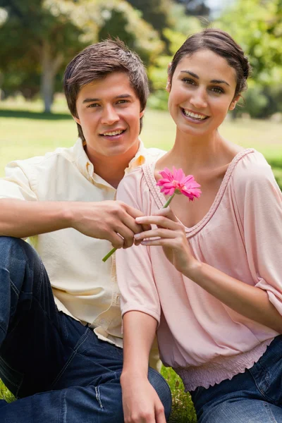 Man giving a flower to a woman as they both look ahead — Stock Photo, Image