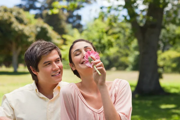 Man tittar på sin vän medan hon är att lukta en blomma — Stockfoto