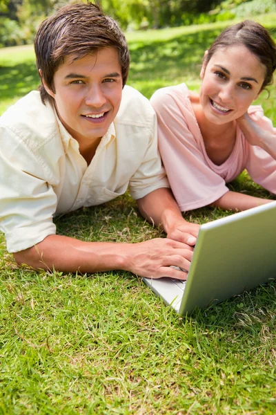 Dois amigos olhando para o lado ao usar um laptop — Fotografia de Stock
