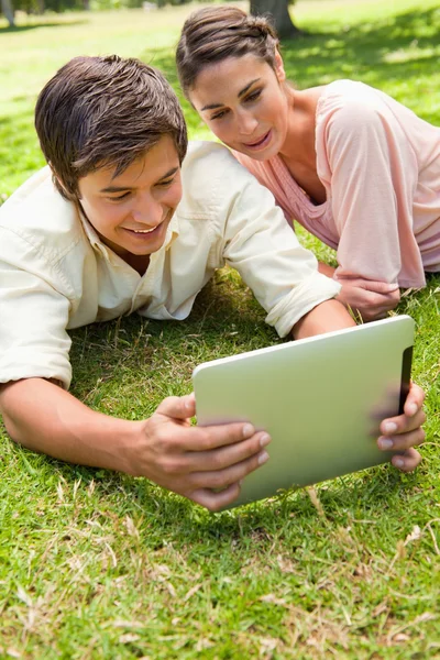 Dois amigos sorrindo enquanto assistem algo em um tablet juntos — Fotografia de Stock