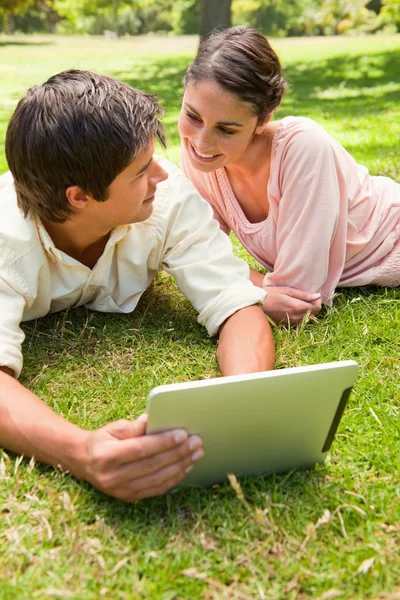 Two friends looking at each other while using a tablet together — Stock Photo, Image
