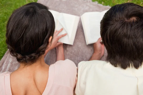 Вид ззаду двох друзів, які читають на ковдрі — стокове фото