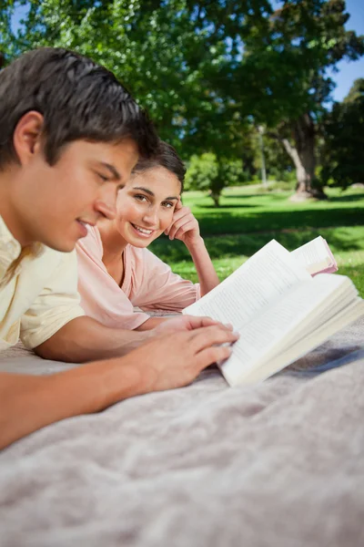 Mulher olhando para o lado como ela lê com seu amigo em um parque — Fotografia de Stock