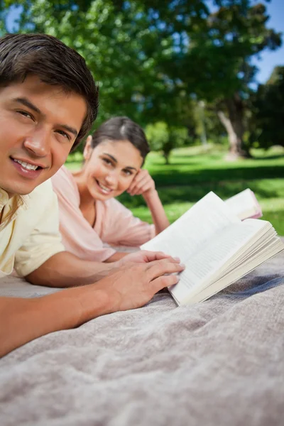 Dwóch przyjaciół, patrząc z boku podczas czytania w parku — Zdjęcie stockowe