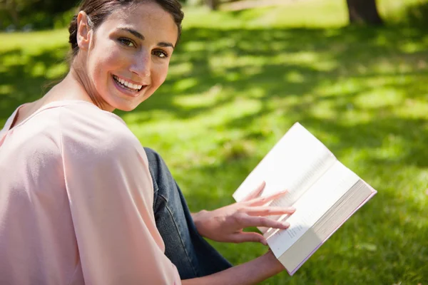 Frau schaut beim Lesen eines Buches im Gras zur Seite — Stockfoto