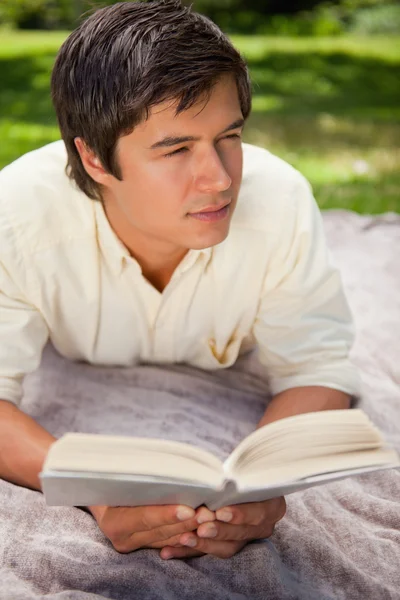 Man op zoek naar zijn kant tijdens het lezen van een boek als hij op een bla ligt — Stockfoto