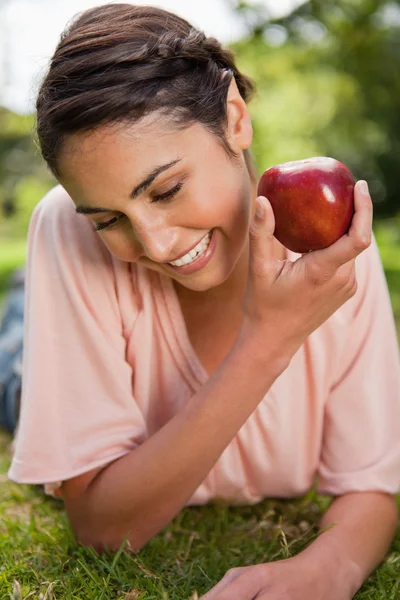 Femme regardant vers le bas tout en présentant une pomme — Photo