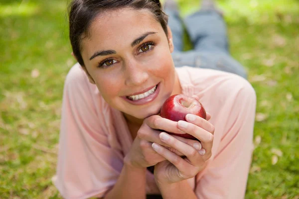 Woman looking ahead while holding an apple — Stock Photo, Image