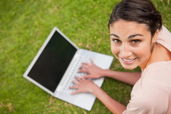 Mulher olhando para o seu lado ao usar um laptop — Fotografia de Stock