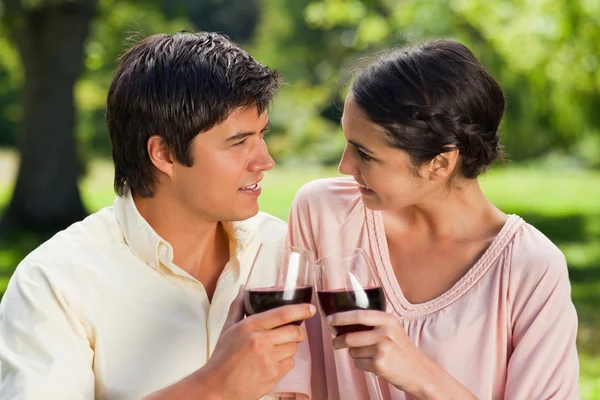 Dos amigos mirándose mientras tocan vasos de vino — Foto de Stock