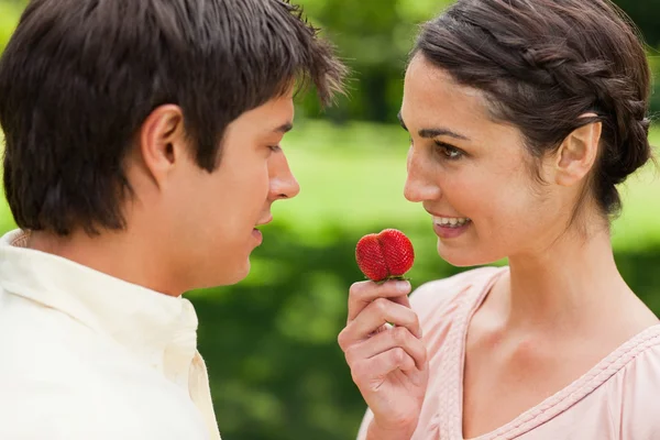 Woman looking at her friend while holding a strawberry — Stock Photo, Image