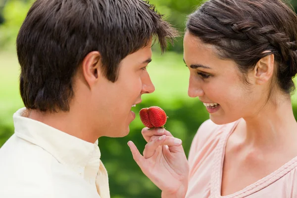 Mujer sonriendo mientras ofrece una fresa a su amigo — Foto de Stock