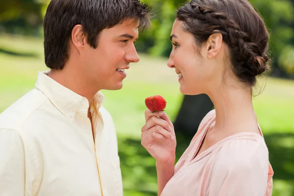 Hombre sonriendo mientras se le ofrece una fresa por su amigo — Foto de Stock