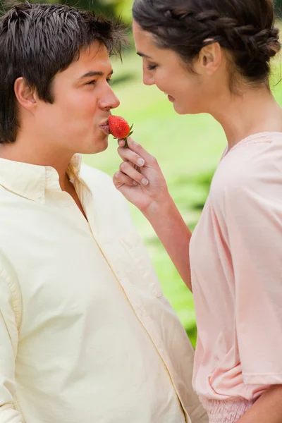 Kvinna som matar en jordgubbe till sin vän — Stockfoto