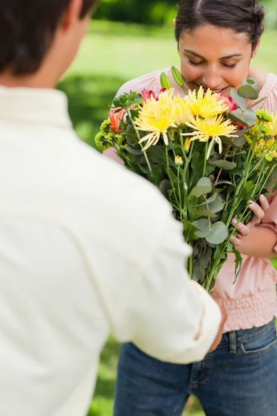 Жінка пахне квітами, які їй дарує друг — стокове фото