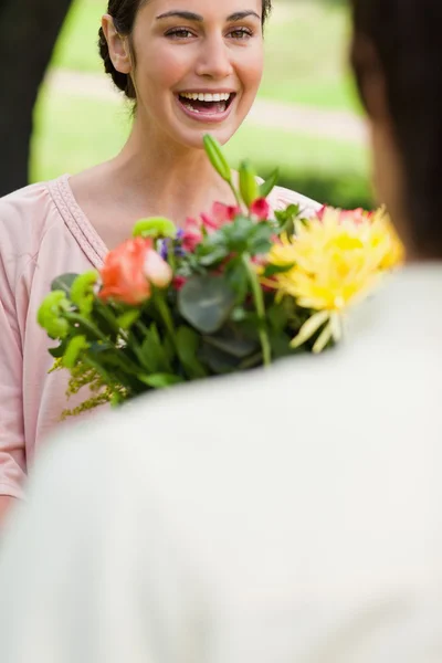 Woman laughing as she is being presented with flowers — Stock Photo, Image