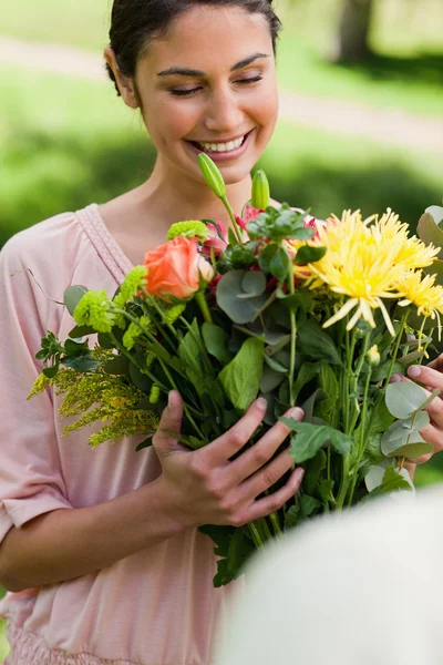 Frau betrachtet Blumen, die ihr geschenkt wurden — Stockfoto