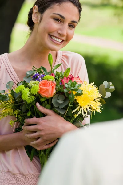 Woman holding flowers which she has been given — Stock Photo, Image