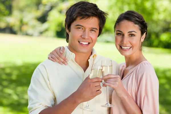 Двоє друзів посміхаються, торкаючись келихів шампанського — стокове фото