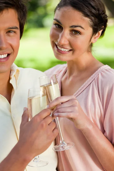 Mujer sonriendo mientras toca copas de champán con su amigo —  Fotos de Stock