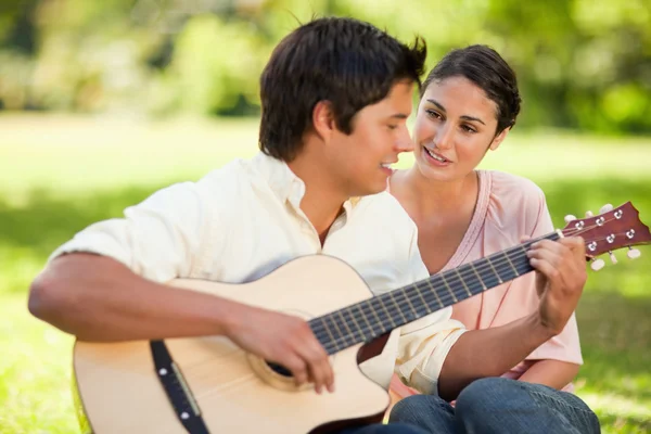 Člověk hraje na kytaru, zatímco jeho přítel mu hodinky — Stock fotografie