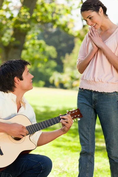 Vrouw stond in bewondering van haar vriend, die de gu speelt — Stockfoto