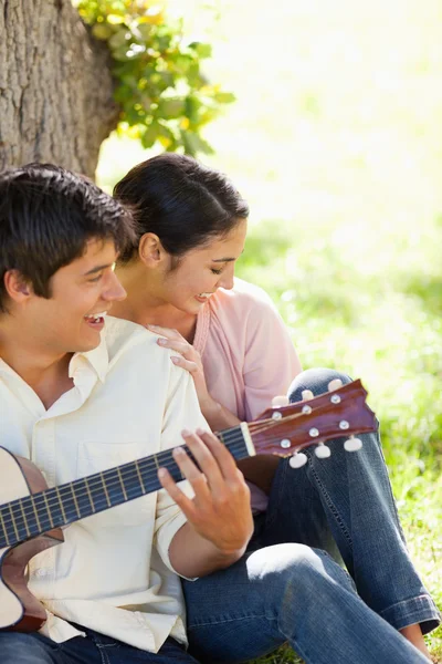 Woman laughing with her friend who is playing the guitar — Stock Photo, Image