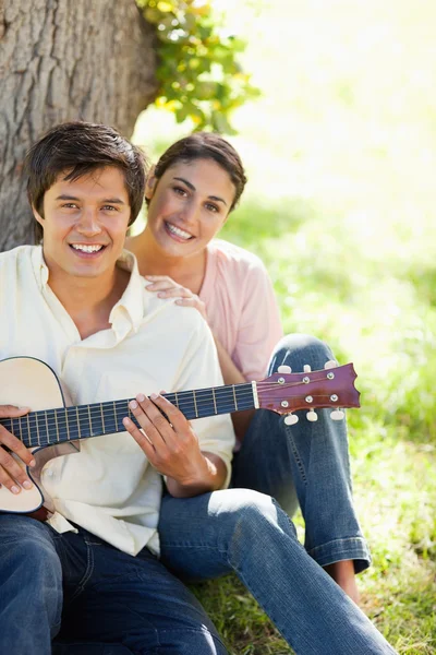Mulher sorrindo com seu amigo que está segurando uma guitarra — Fotografia de Stock