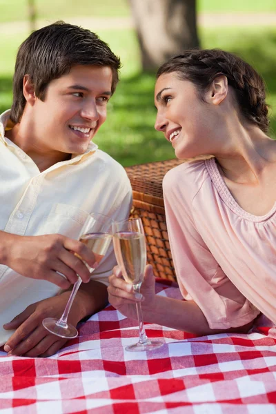 Twee vrienden op zoek naar elkaar een glimlachend tijdens een picknick — Stockfoto