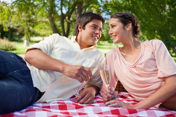 Two friends looking at each other while holding glasses during a — Stock Photo, Image